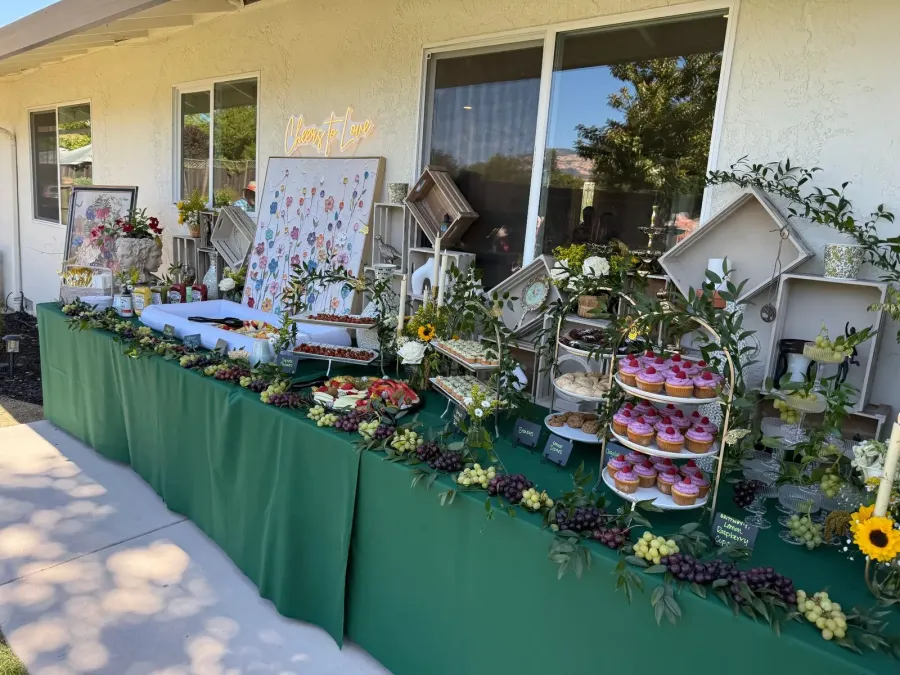 Shower sweets and grazing spread softened with roses and greenery tucked between cupcakes and fruit — floral shower styling for Sonoma catering