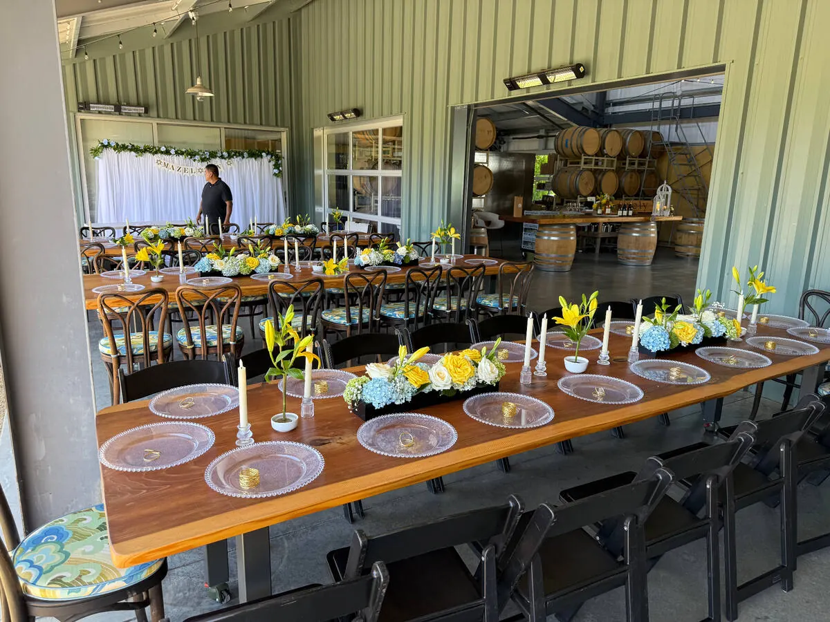 Low floral centerpieces and taper candles running down a long dinner table at a St. Helena event by Napa Catering Company