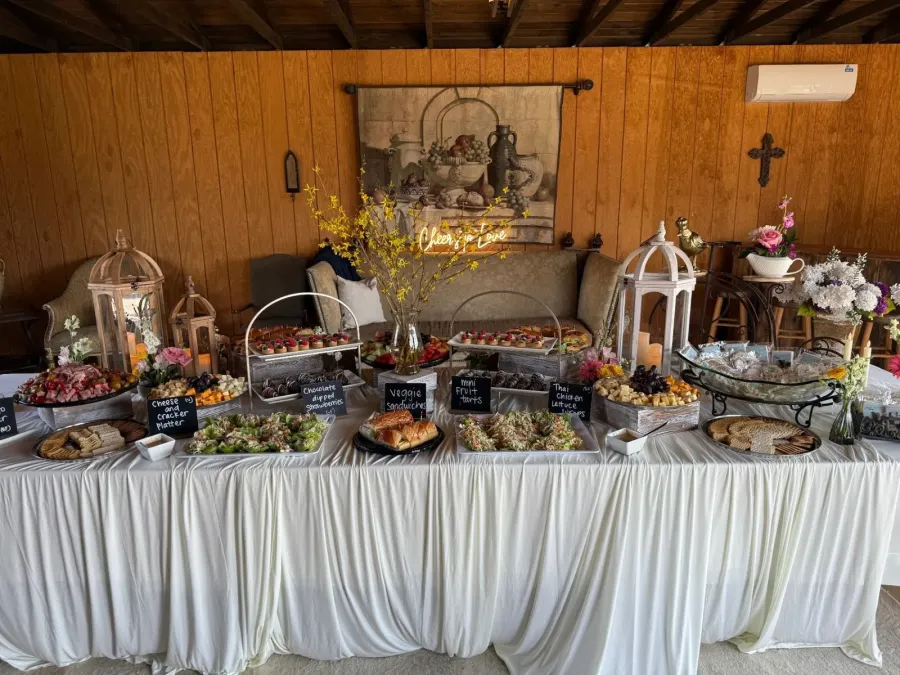 Grazing table of meats, sandwiches and fruit tarts punctuated with low bud vases along its length — floral-styled grazing tables for Napa and Vallejo catering