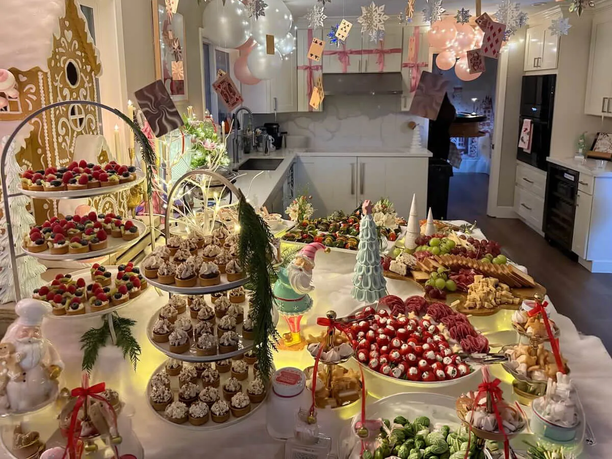 Themed party tablescape where tiered tarts and cupcakes sit beneath pastel balloons and fresh blossom accents — floral party styling for Fairfield catering celebrations